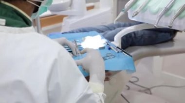 Klinikteki hastayı tedavi ederken diş kelepçelerini kullanan üniformalı tanınmayan bir dişçi.