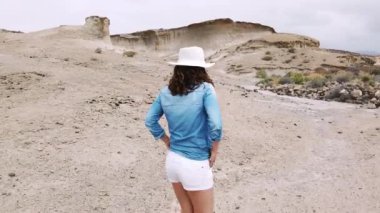 Beyaz şapkalı güzel bir kadın dağda yürüyor. 