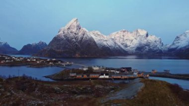 Lofoten Adaları 'ndaki küçük kıyı kasabasının yerleşim yerlerinin resimli hava manzaralı manzarası Norveç' te akşam gökyüzüne karşı kayalık dağlarla kaplı.