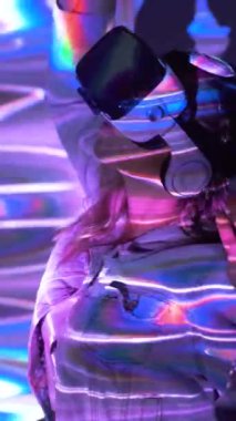 Parlak neon ışıklarla VR kulaklıklardan dans eden anonim kadının yan görüntüsü