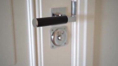 Açık minimalist iç kısımda gümüş saplı kapalı beyaz kapı.