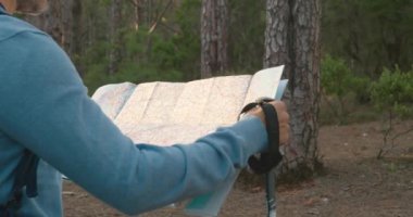 Sırt çantalı ve bastonlu isimsiz bir adam hafta sonu ormanda yürüyüş yaparken kağıt haritasını inceliyor.