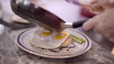 Tanımlanamayan aşçı tavadan krema sosu ekliyor ve kahvaltıda masada servis ediliyor.