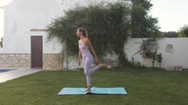 Bahçede yoga egzersizi yapan genç bir kadın.