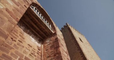 Tepsinin altından, güneşli bir günde mavi bulutsuz gökyüzünün arka planında taş cepheli kuleleri olan antik kalenin sağ görüşü.