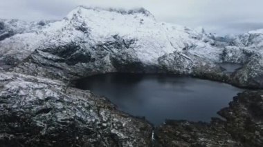 Norveç 'te bulutlu bir günde karla kaplı kayalık dağlarla çevrili krater göllerinin nefes kesici manzarası.