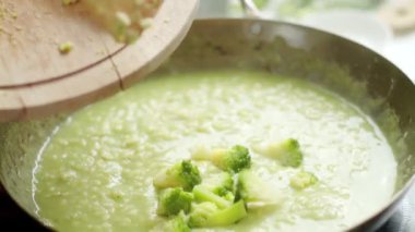Kimliği belirsiz aşçıya yakın çekim. Fırında pilav pişirirken tavaya taze yeşil brokoli ilave ediliyor.
