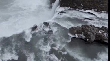 İzlanda 'da kasvetli bir günde kayalık kayalıklardan akan güçlü şelalenin nefes kesici manzarası.