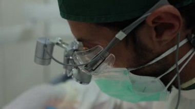 Dürbünlü erkek dişçi ve üniformalı modern diş kliniğinde çalışıyor.
