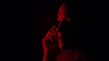 Stüdyonun arka planında kırmızı ışıkta makyaj yapan kadın silueti. 