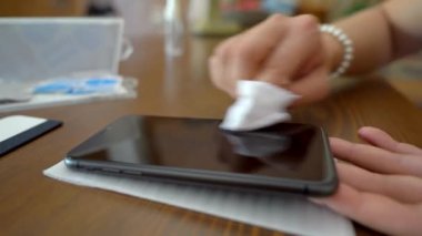 Tamir atölyesinde çalışırken modern cep telefonunun ekranından deterjanı silen isimsiz kadın teknisyenin yumuşak odağı