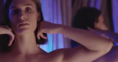 Dantelli sütyen ve ipek gecelikli genç esmer. Saçlarına dokunuyor. Kamerayla flört ediyor.