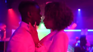 Gece kulübündeki partide renkli neon ışığa karşı dans eden mutlu siyah çift.
