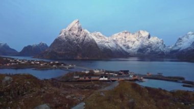 Lofoten Adaları 'ndaki küçük kıyı kasabasının yerleşim yerlerinin resimli hava manzaralı manzarası Norveç' te akşam gökyüzüne karşı kayalık dağlarla kaplı.
