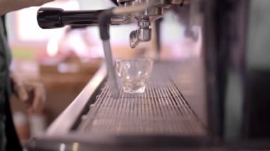 Kırpılmış arka planda, açık kahve makinesinde kahve demleyen, cam bardaklı tanınmaz halde duran kahve makinesi.