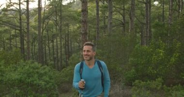 Sırt çantalı ve bastonlu yetişkin bir adamın gündüz vakti yeşil ağaçlıklarda yürüyüş yaparken fotoğrafını çekiyorum.