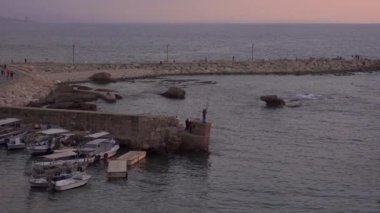 Lübnan 'da günbatımına karşı dalgalı denizle yıkanmış eski limanın huzurlu manzarası.