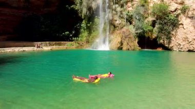 Çok ırklı erkek ve kadın yaz tatili boyunca temiz göl suyunda şişme şamandıralarda uzanırlar.
