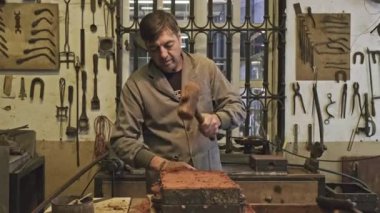 Kum döküm işlemi sırasında kuyumcu atölyesinde kalıp kutusuna kum dolduran profesyonel aletli yetenekli erkek üstadın yan görünüşü