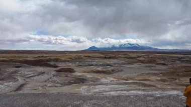 Sıcak giysiler içinde, Wayne County 'deki Fabrika Butte' ta, tepenin zirvesinde duran ve manzaralı vahşi vadiye hayran olan uzaktan kumandalı hava aracı görüntüsü.