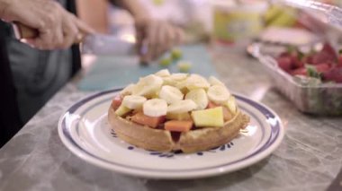 Masada servis edilen ev yapımı waffle 'lara taze üzüm ekleyip kesen tanınmamış kadın aşçı.