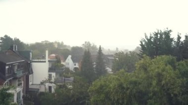 Şiddetli yağmur damlalarıyla fırtınalı bir hava şehrin çatısına düşüyor.