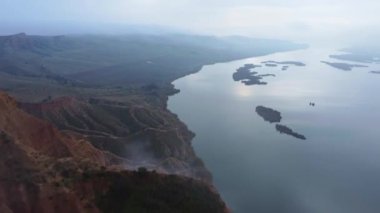 Toledo 'da sisli bir günde sakin bir nehir ve yeşil arazinin yakınındaki dağ sırtı yavaş çekimde insansız hava aracı görüntüsü