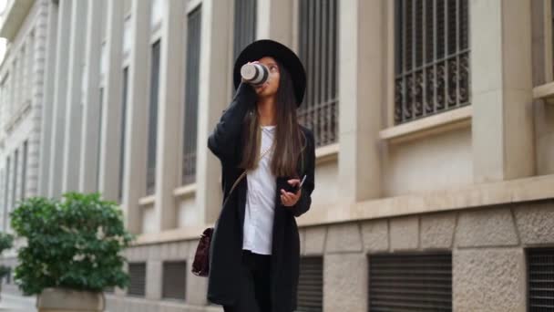 身穿时髦服装 头戴一顶现代手机和外卖热饮的西班牙女性 — 图库视频影像