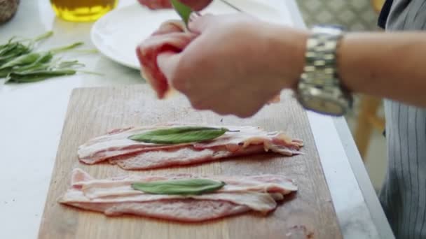 不具名的女性在厨房里把未煮熟的小牛肉片和深菜和鼠尾草放在木制绞架上的真实时间 — 图库视频影像