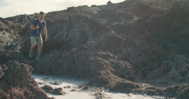 テネリフェ島 カナリア諸島 スペインの海洋保護区近くの火山海岸でウォーキングスティックでカジュアルな服で成熟した男性の追跡ショット — ストック動画
