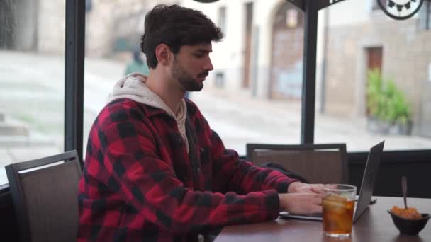 커피숍에서 테이블에 근처에 앉아있는 노트북을 입력하는 소다를 마시는 남자의 — 비디오