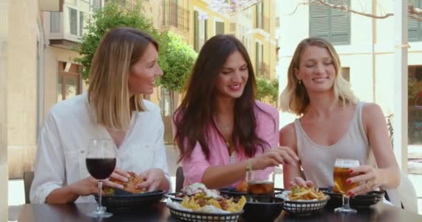 一群时髦漂亮的成年女性一边大声大笑 一边在人行道上的咖啡店里与酒水共享美味的小吃 — 图库视频影像