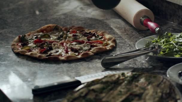 レストランキッチンで作業しながら 大理石のカウンターで焼きたての食欲をそそるホットピザを切断ミステリー匿名のピザメーカー — ストック動画