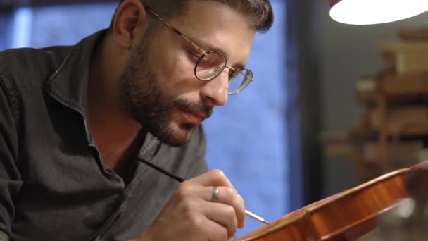 Adulto Artesão Óculos Sentado Mesa Luthiery Coloração Montado Violino Madeira — Vídeo de Stock