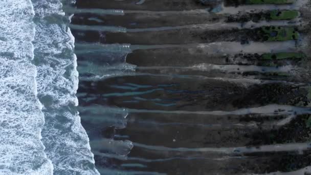 カボラソスの海岸に黒い砂で荒い岩の形成を洗浄する青いクリスタルの透明な海水のトップビューの美しい風景 — ストック動画