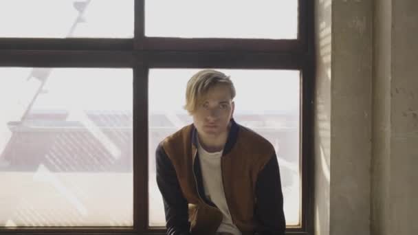 Attraktiver Modischer Junger Blonder Mann Sitzt Auf Der Fensterbank Neben — Stockvideo