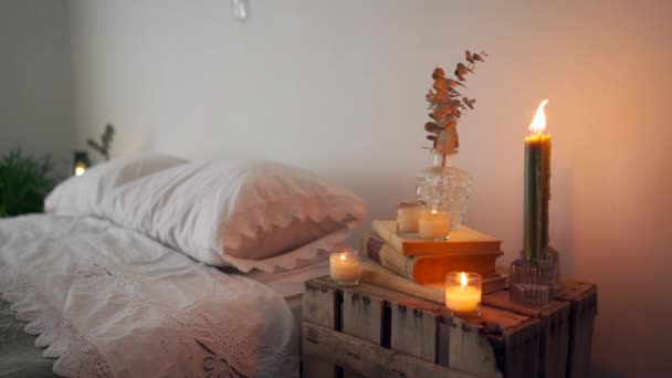 房间里的碎片 用生疏的木制手工制作的床头柜和玻璃瓶中的干植物堆放在一堆靠近蜡烛的旧书上 — 图库视频影像