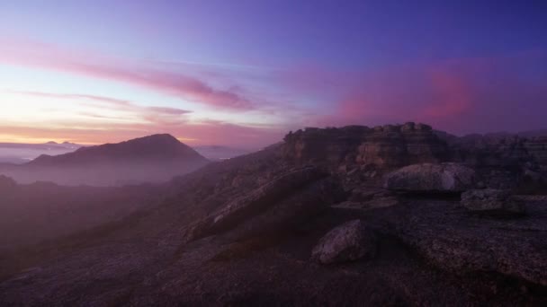 低い雲で空の下のいくつかの岩山の上の日の出の風景 — ストック動画