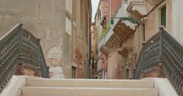 運河の上の古いレンガの橋を歩き イタリアでの休暇中にヴェネツィアシティを探索しながら歴史的な建物を賞賛する女性 — ストック動画