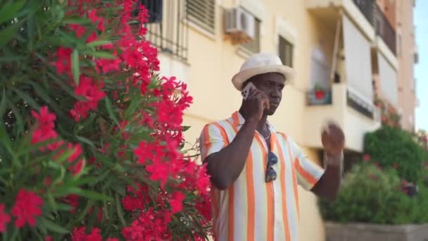 夏天的一天 一个乐观的非裔美国商人站在灌木丛边打盹和打电话聊天的真实时间 — 图库视频影像