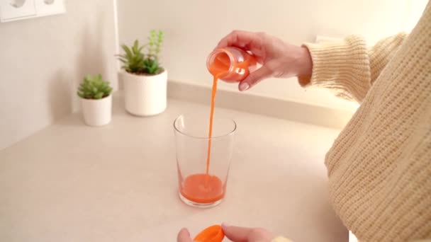 女人在厨房里把新鲜果汁倒进杯子里 — 图库视频影像