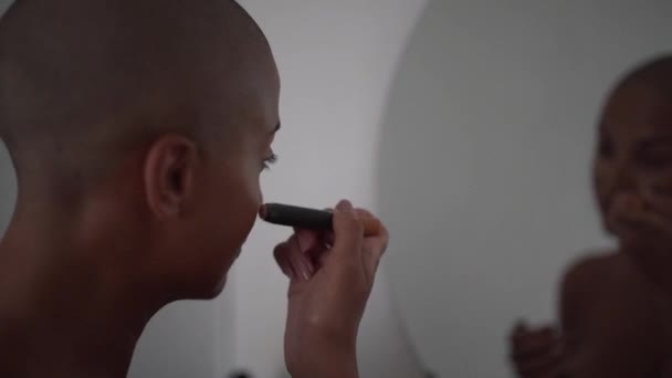 集中アフリカ系アメリカ人女性で ハゲのあるヘアカットが鏡を見て メイクをしながらブラシでファンデーションを適用 — ストック動画
