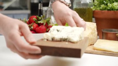 Ekin aşçısı parmesanlı kesme tahtası ve masaya pirinçli kase ve zeytinyağlı fesleğen koyuyor.