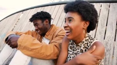 Genç Afrikalı çift birlikte oturup gülüyor.