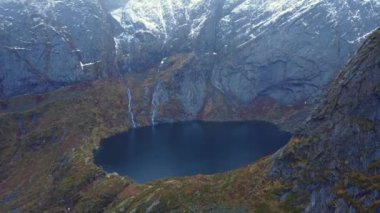 Devasa kayalık dağlardan akan şelalelerin muhteşem drone görüntüsü ve kışın Lofoten 'deki krater gölüne düşüşü.