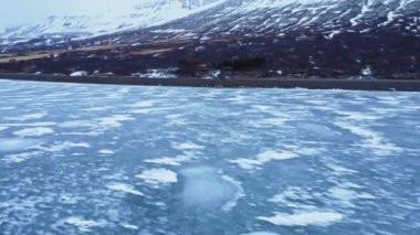 İzlanda 'nın bulutlu bir gününde Vatnajokull Ulusal Parkı' nın volkanik arazisinde karlı dağlarla çevrili denizde yüzen buz parçalarının manzarası.