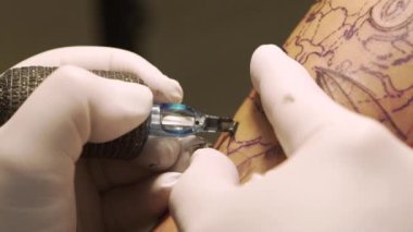 Stüdyoda genç bir kadının koluna dövme yapan dövme sanatçısı.