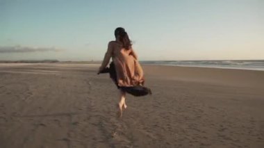 Levante 'de rüzgarlı bir günde kumsalda koşan kaygısız, çıplak ayaklı bir kadın.