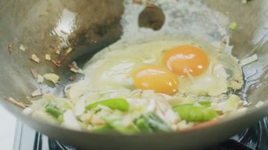 Tavaya çiğ yumurta, sebzeler ve ahşap spatulayla karıştırılmış malzemeler ekleme ihtimali yüksek.