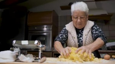 Son sınıf öğrencisi kadın mutfakta oturmuş hamuru yoğururken aynı zamanda iştah açıcı tortellini hazırlıyor.